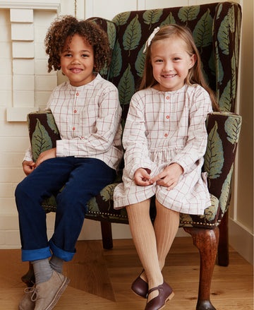 Boy and girl sitting in a chair wearing Burgundy Check products