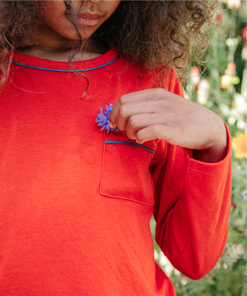 GIrl in red shirt putting flower in pocket