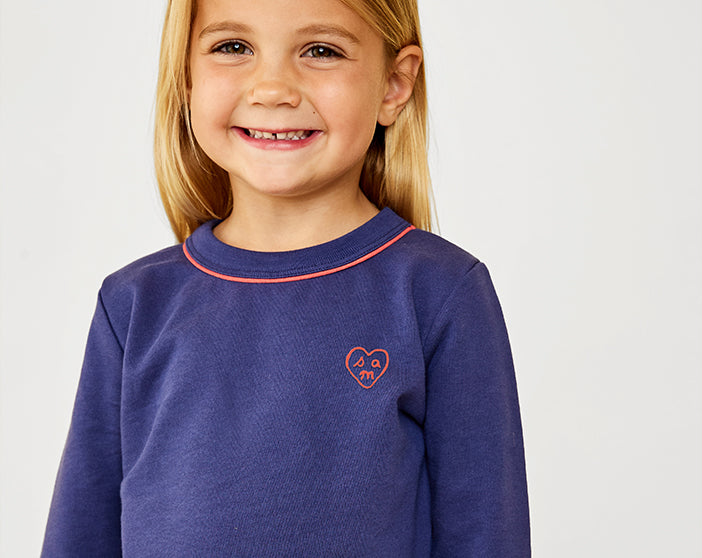 Girl smiling wearing Navy Remy Sweatshirt embroidered with heart and letters s, a, and m